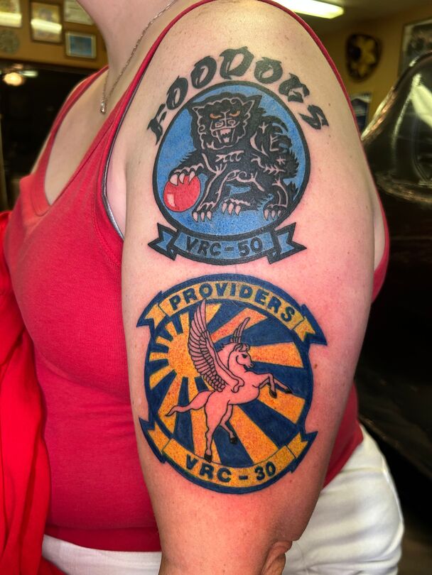 Tattoos on a person's upper arm. Top tattoo: