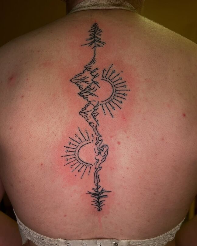 Back tattoo: vertical mountain, sun, and tree design in black ink.