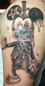 Tattoo of a decayed Mickey Mouse with a sword through the head, a star on one ear, and a zombie-like appearance.