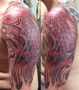 Red koi fish tattoo on a person's upper arm, featuring waves in black and gray.