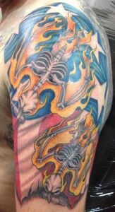 Tattoo on an arm: burning skeletal figures with a star field and flag-like design. Orange, blue, and red colors.