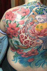 Colorful back tattoo: Koi fish swimming through water and flowers.