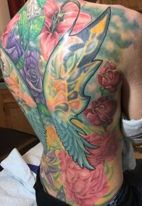 Full back tattoo of colorful flowers and angel wings.