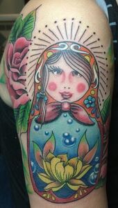 Colorful Matryoshka doll tattoo on arm with a rose.