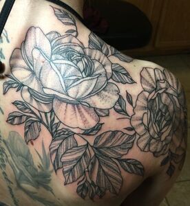 Black and white rose tattoo on a shoulder and arm, with leaves and shading.