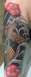 Tattoo of a samurai helmet with flowers and water waves in dark blue, red, and gold colors on an arm.