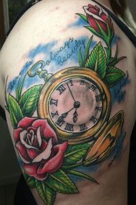 Tattoo on shoulder: gold pocket watch with roses and green leaves, surrounded by blue sky and the words