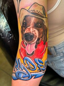 Tattoo of a dog wearing a cowboy hat and red bandana, with