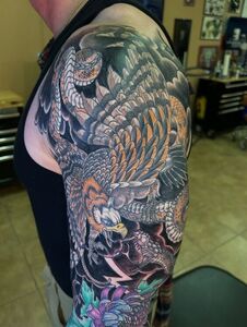 Tattoo sleeve: eagle attacking snake, with colorful floral and lightning design.