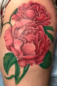 Tattoo of two red peony flowers with green leaves on skin.