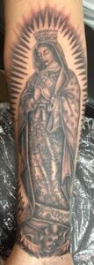 Tattoo of the Virgin Mary on an arm, in grayscale, with a halo and crown.