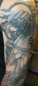 Grim Reaper tattoo on an arm, holding a scythe, in a moonlit sky.