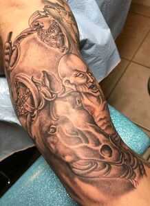 Black and white tattoo on an arm, depicting a horse, rider with fierce expression, and ornate details.