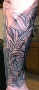 Tattoo of a black and gray floral design on an arm.