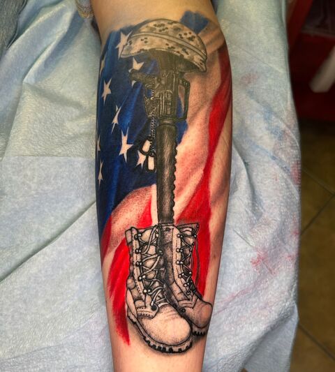 Memorial boots and rifle tattoo over an American flag
