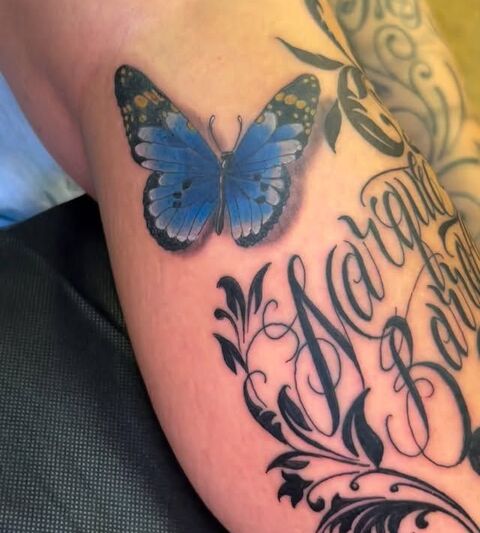 Blue butterfly and script lettering tattoo