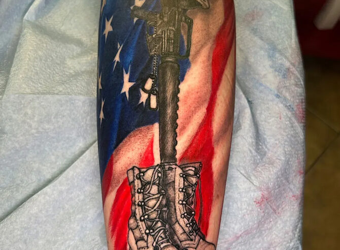 Black and grey combat boots and rifle memorial tattoo over a color American flag